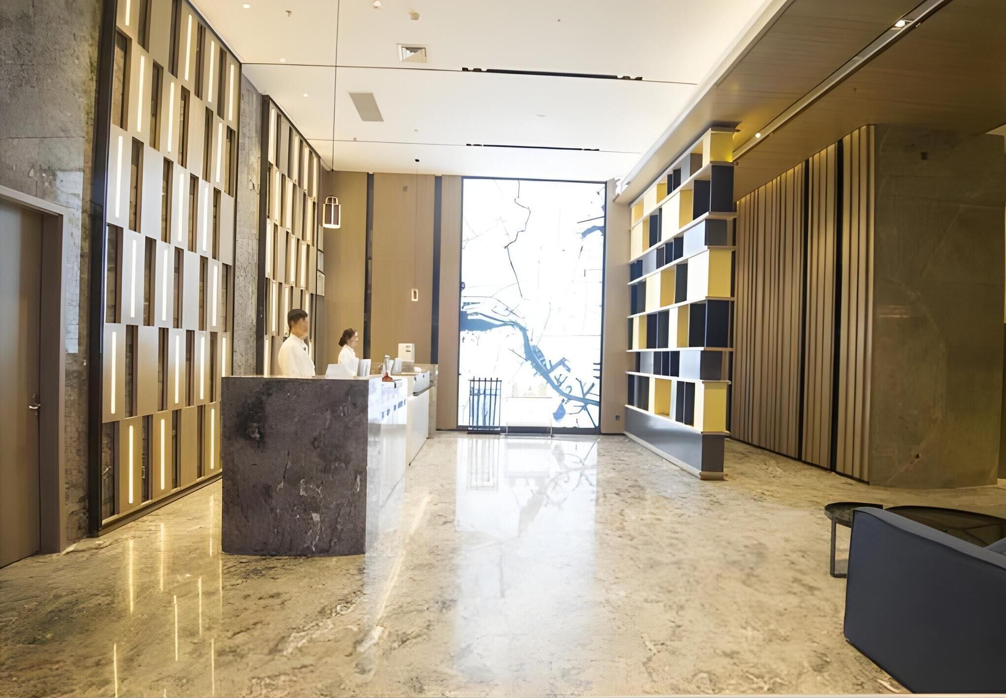 A modern lobby with a marble floor, a reception desk, and a large glass door leading outside.