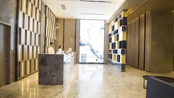 A modern lobby with a marble floor, a reception desk, and a large glass door leading outside.