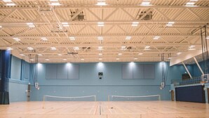 An indoor sports hall with a basketball court, a volleyball net, and a climbing wall. - Warwick Conferences - Radcliffe House (Coventry)