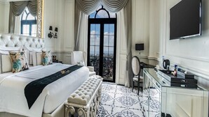 A luxurious bedroom with a large bed, a view through a window, a television, and a desk with a chair. - Mare Hotel (Apokoronas)