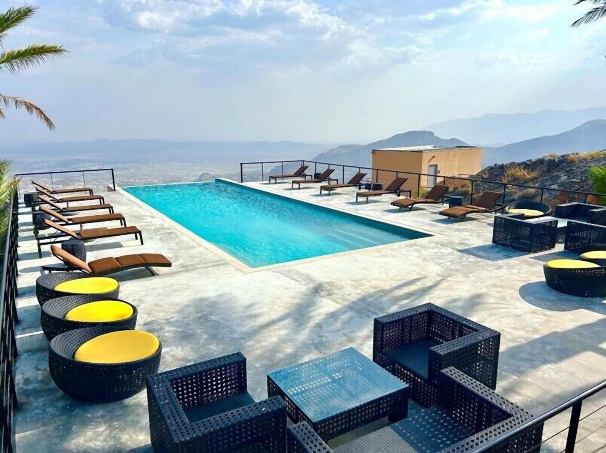 Piscina no terraço com espreguiçadeiras e móveis de vime.