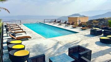 Piscina no terraço com espreguiçadeiras e móveis de vime.
