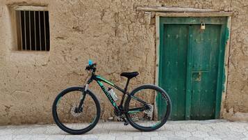 Uma bicicleta estacionada em frente a um edifício rústico com porta verde e janela com grades.