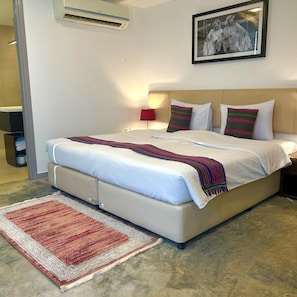 Una habitación de hotel con una cama, una mesita de noche, una lámpara, un cuadro en la pared y una alfombra roja.