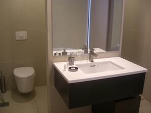 Un baño con un lavamanos blanco, un espejo y un inodoro.