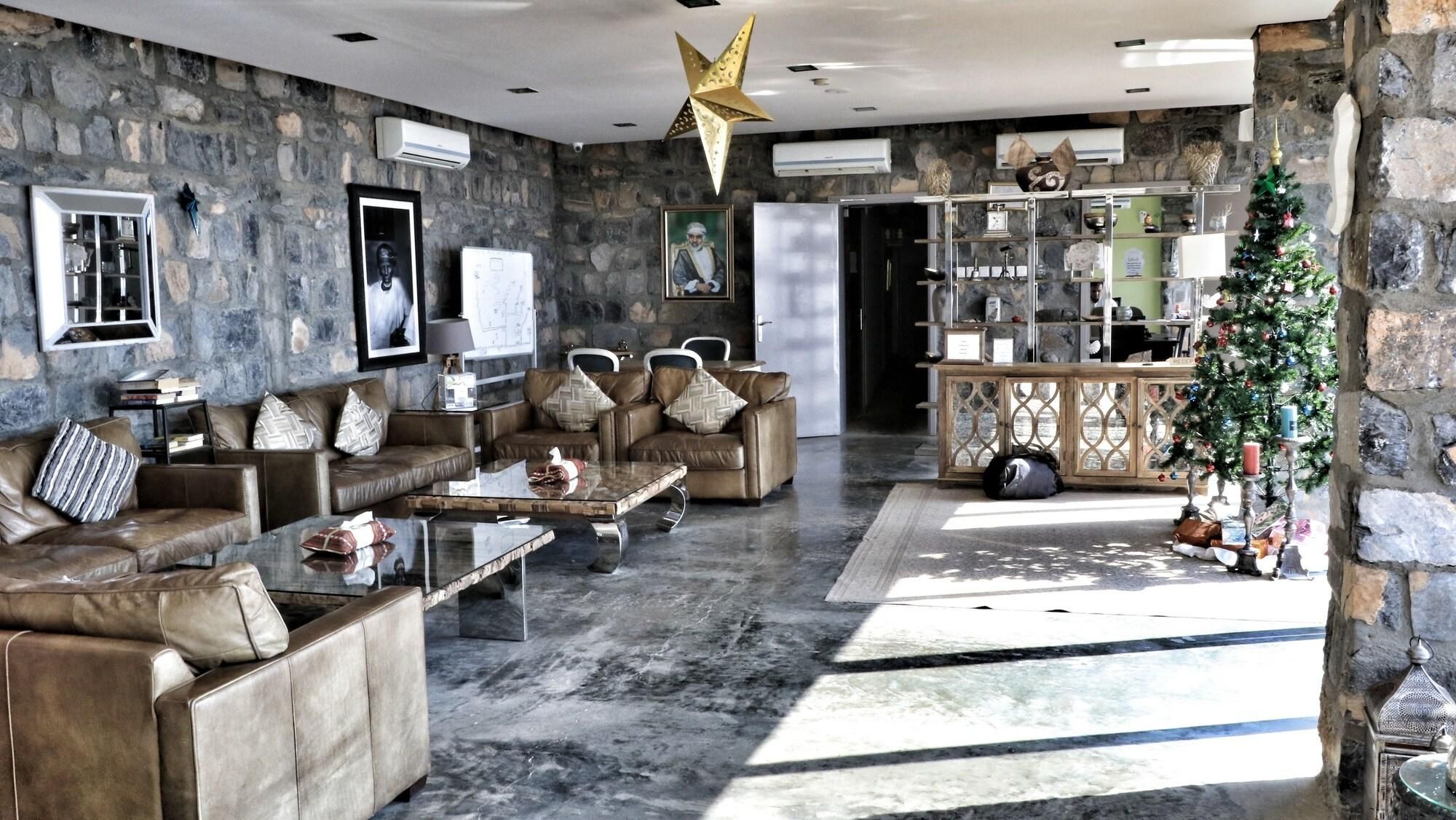 Un salón con paredes de piedra, sofás de cuero, una mesa de centro y un árbol de Navidad.