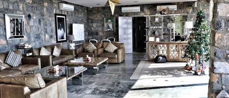 A stone-walled living room with leather sofas, a coffee table, and a Christmas tree.