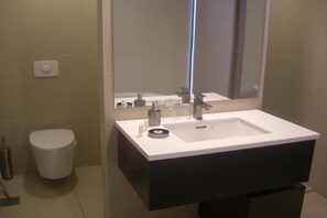 A bathroom with a white sink, a mirror, and a toilet. - The View (Al Hamra)