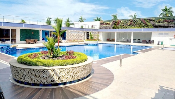 Ein moderner Hotelpoolbereich mit einem runden Mosaik-Pflanzgefäß, Liegestühlen und einer begrünten Wand.