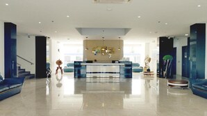 Eine geräumige Lobby mit einer Rezeption, einer Treppe und einem großen Fenster, das für natürliches Licht sorgt.