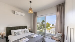 A modern hotel room with a large bed, a view of the outdoors, and a balcony.
