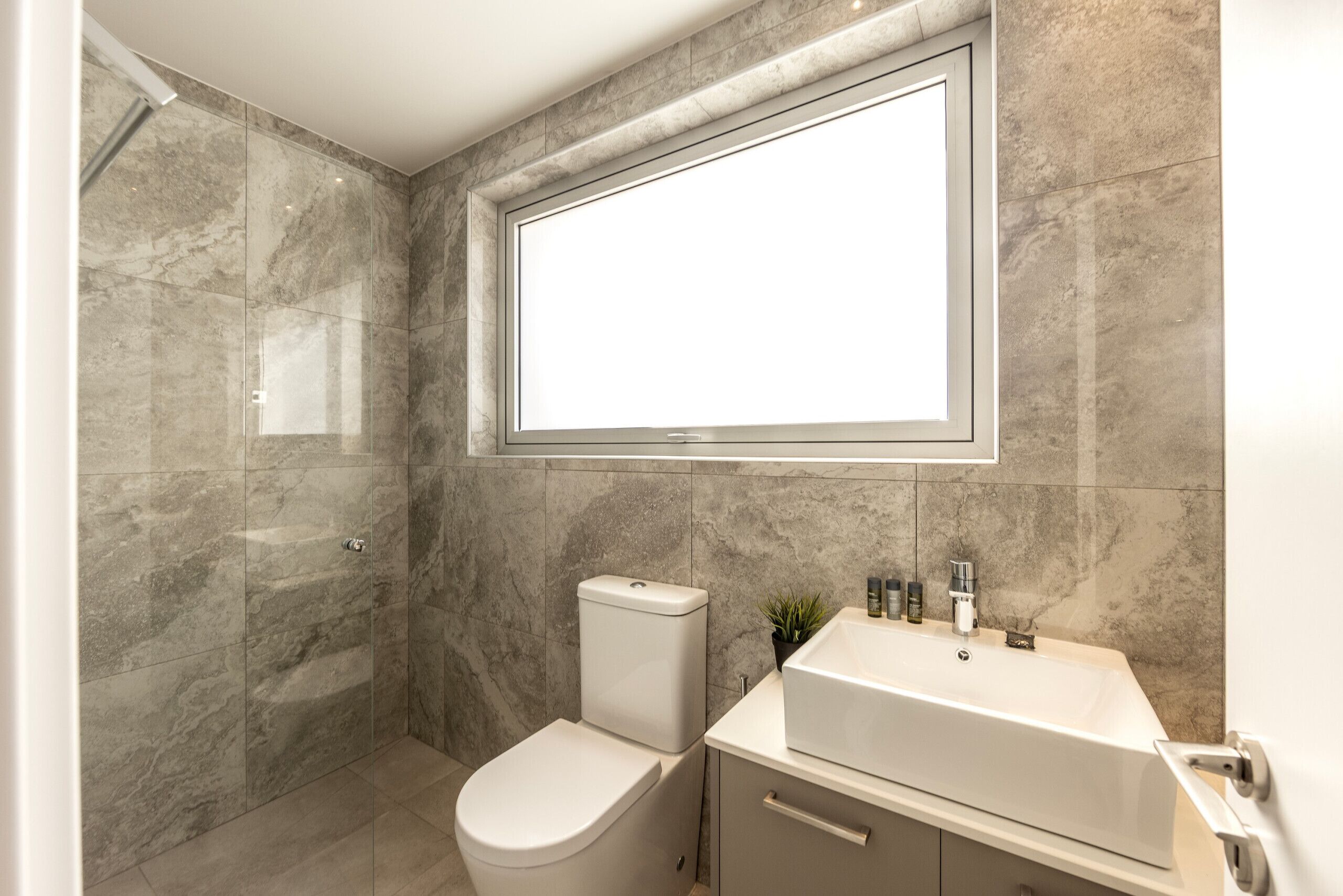 Un baño moderno con ducha, inodoro y lavamanos.