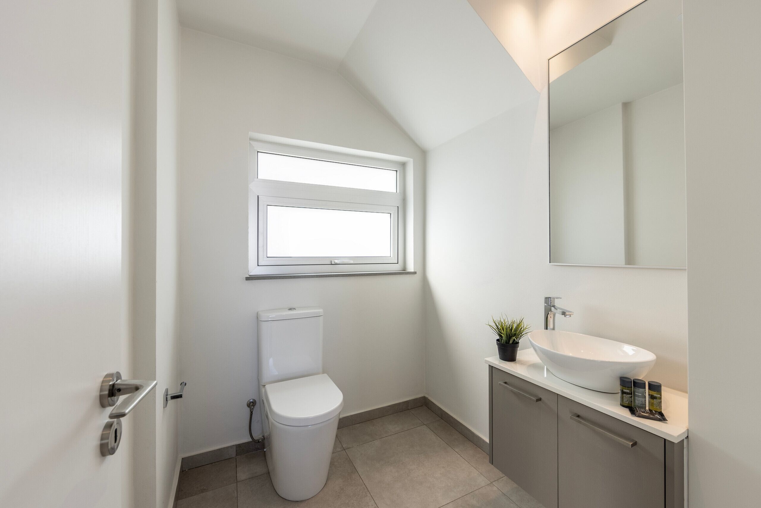 A modern bathroom with a toilet, a sink, and a window.
