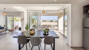 A modern dining area with a large table, three chairs, and a view of the outdoors.
