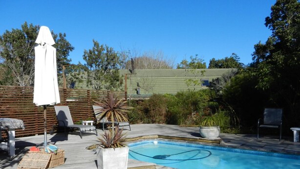 A backyard with a swimming pool, a covered patio area, and outdoor furniture. - Tsitsikhaya Lodge (Storms River)