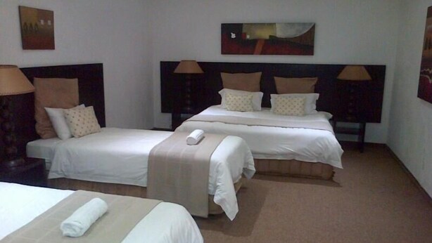 Ein Hotelzimmer mit zwei Einzelbetten, einem Sofa und einem kleinen Tisch.