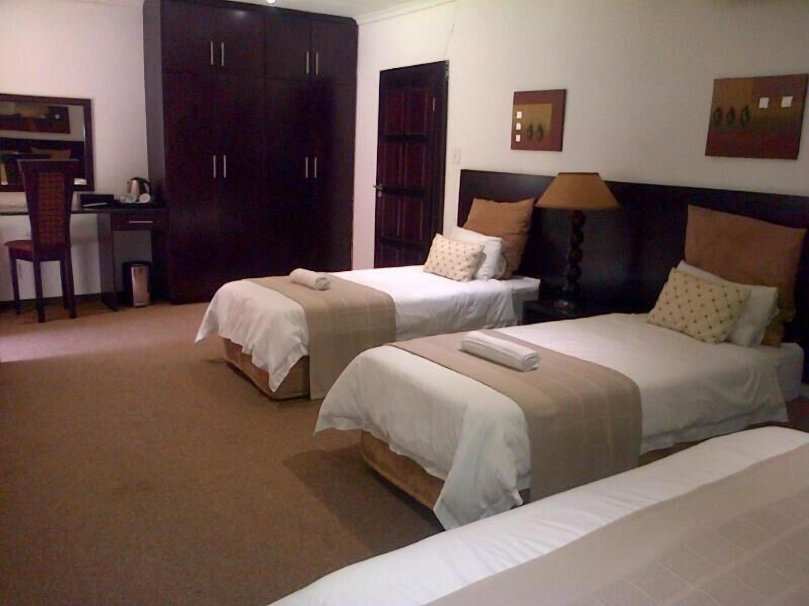 Habitación de hotel con dos camas, un escritorio y un armario.