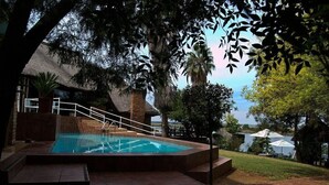 Una piscina con escalones de acceso, rodeada de árboles y vistas al mar.