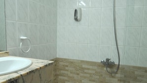 A bathroom with a marble countertop, a sink, a shower with a handheld showerhead, and a patterned tile backsplash. - Maria Rosa (Pedrola)
