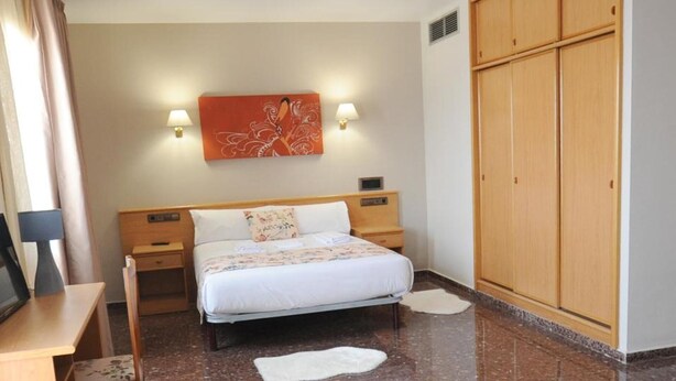 A hotel room with a bed, bedside tables, a desk, a wardrobe, and a wall-mounted artwork. - Maria Rosa (Pedrola)