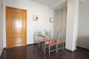 A hallway with a wooden door, a dining table with chairs, and two framed pictures on the wall. - Maria Rosa (Pedrola)