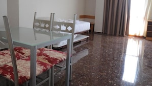 A hotel room with a glass dining table, two chairs, a bed, a nightstand, a painting on the wall, and a window with curtains. - Maria Rosa (Pedrola)