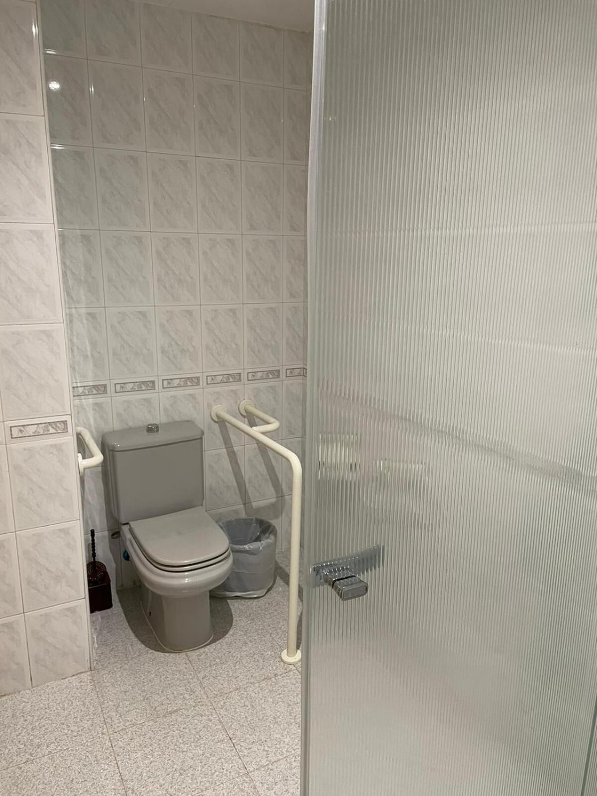 Un baño con inodoro, bidé y cabina de ducha de vidrio.