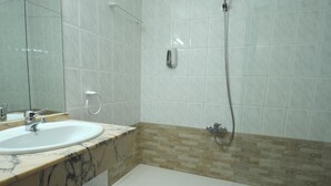 A bathroom with a marble sink, a mirror, a shower, and a tiled wall. - Maria Rosa (Pedrola)