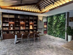 Una biblioteca con estanterías, una mesa, sillas y una pared verde.