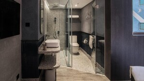 Un bany modern amb un plat de dutxa de vidre, un lavabo independent i un vàter.
