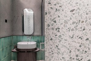 Ein Badezimmer mit einem runden Waschbecken, einem Spiegel und einem Terrazzo-Boden.