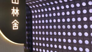 Entrada d'hotel amb un disseny modern, amb una paret de finestres circulars i senyalització il·luminada.