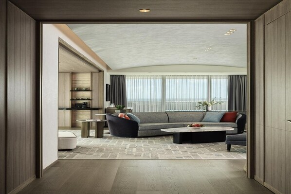 A modern living room with a sectional sofa, a coffee table, and a dining area with a small table and chairs. - City of Dreams Mediterranean (Limassol)