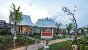 A traditional-style building with a central seating area and a garden with palm trees and potted plants.