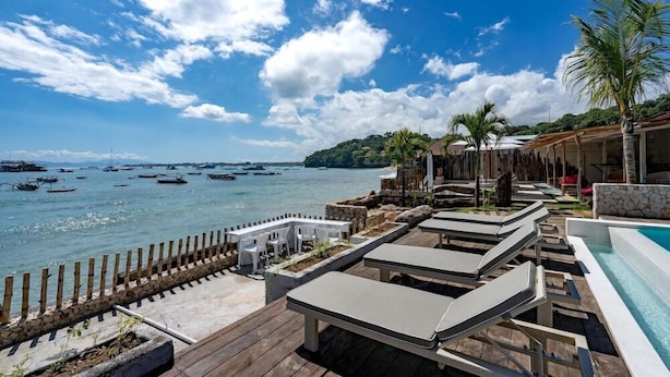 A poolside area with lounge chairs and a view of the sea.