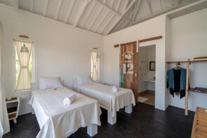 A room with two single beds, a wooden door, a hanging garment rack, and a small table. - Paus Putih Hotel Lembongan (Lembongan Island)
