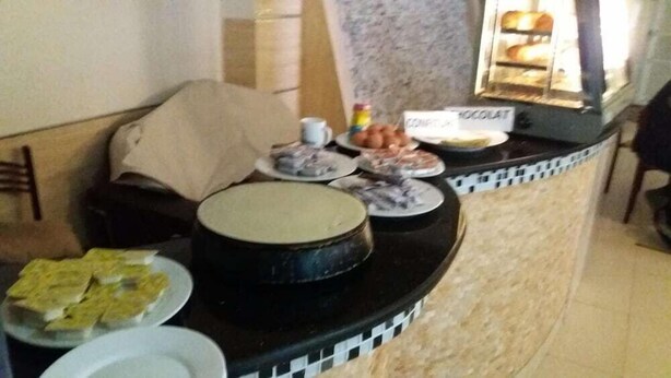 A buffet table with various dishes, including a large cake, plates of food, and a chocolate dessert. - Hotel Privilege (Bir El Djir)