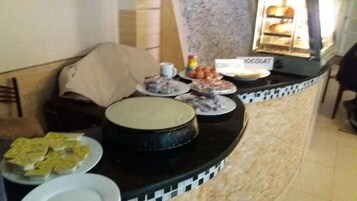 Una mesa de buffet con diversos platos, incluyendo un pastel grande, fuentes de comida y un postre de chocolate.