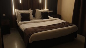 A modern bedroom with a large bed, dark wood paneling, and vertical light strips. - Hotel Privilege (Bir El Djir)
