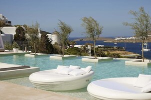 Zona de piscina con sillones de descanso y vista al mar.