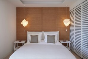 A modern bedroom with a wooden headboard, two bedside tables, and a large bed with white bedding. - Once in Mykonos Luxury Resort - Designed for Adults (Mykonos)