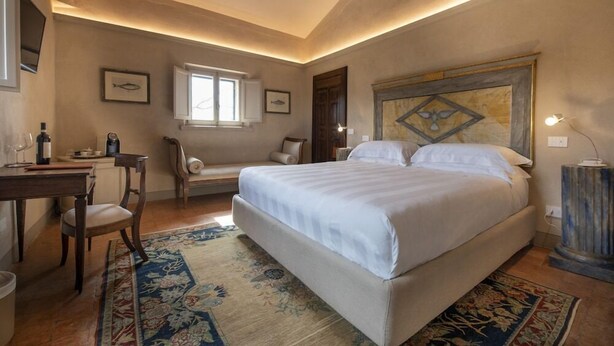 Une chambre à coucher avec un grand lit, un bureau avec une chaise, une fenêtre et une tête de lit décorative.