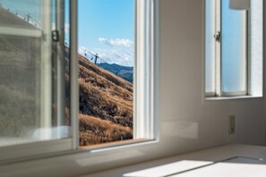 A room with a large window overlooking a hilly landscape with a ski lift.