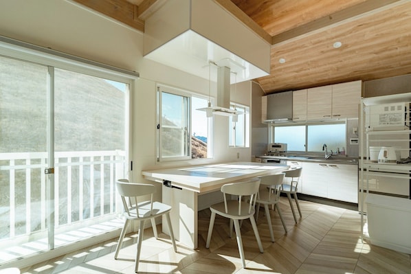 Una cocina moderna con una isla grande, armarios blancos y vistas al exterior.