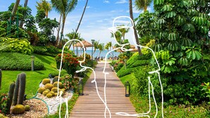 A wooden pathway leading through a tropical garden with palm trees and cacti. - Forest City Eco Stay (Gelang Patah)
