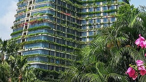 A high-rise building with multiple balconies, surrounded by lush greenery and flowering plants. - Forest City Eco Stay (Gelang Patah)