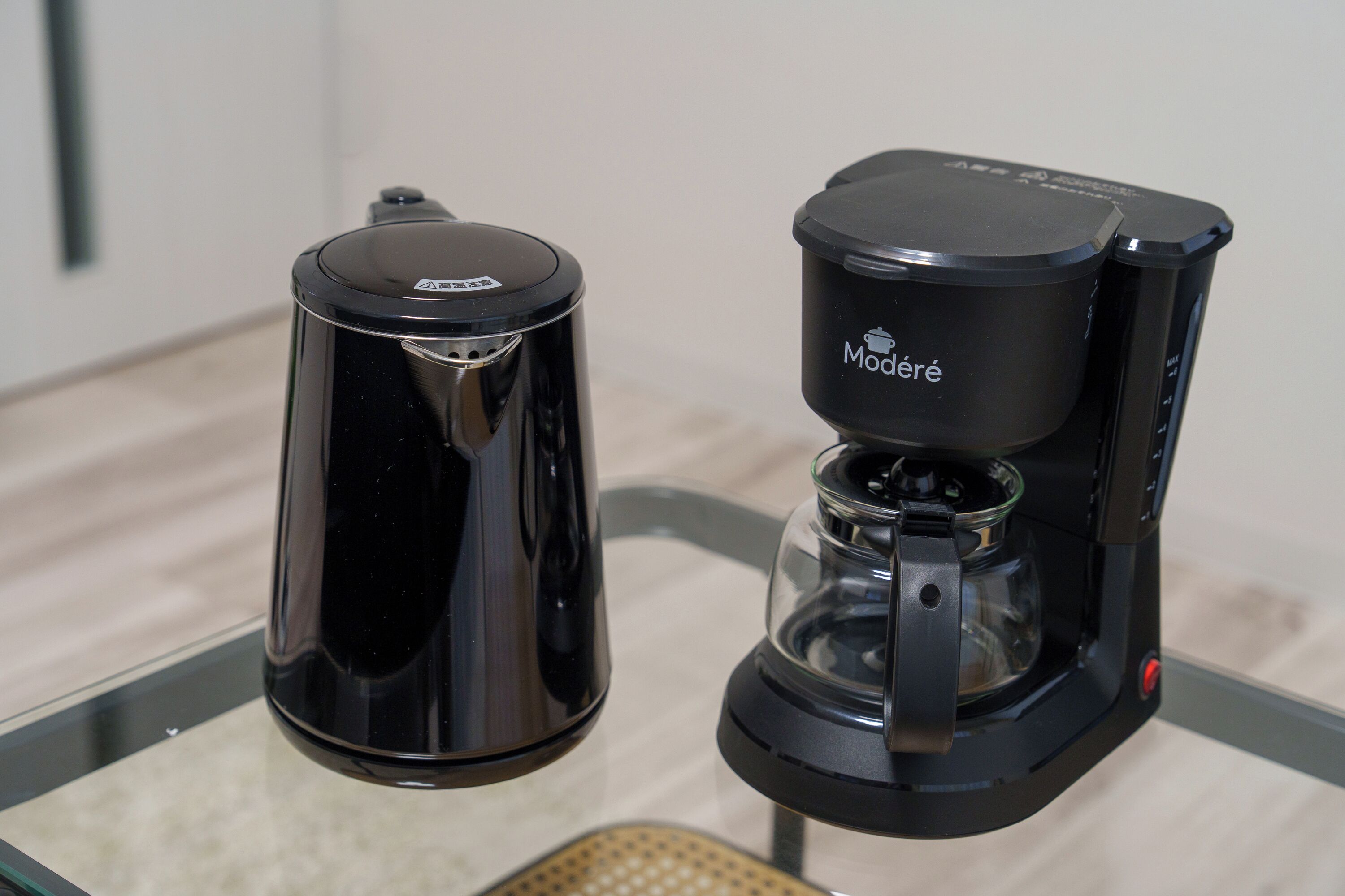 Dos cafeteras negras sobre una mesa de vidrio.