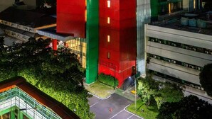Un edificio moderno con una fachada llamativa de color rojo y verde, con la leyenda 'UNJ Centro de Capacitación Universitaria'.