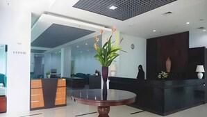 Un área de recepción moderna con una mesa redonda, una planta en maceta y un mostrador de recepción.