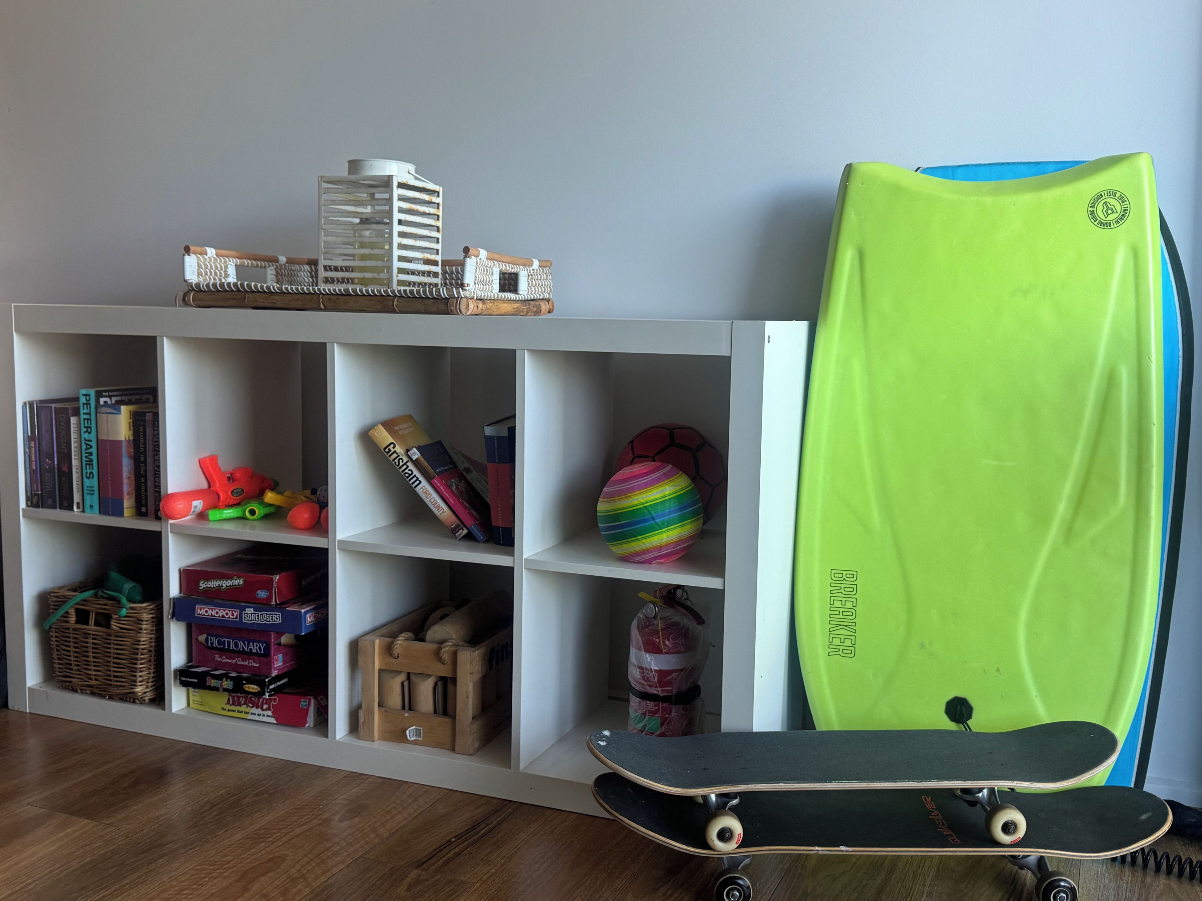 Une pièce avec une bibliothèque contenant des livres, des jouets et un skateboard.